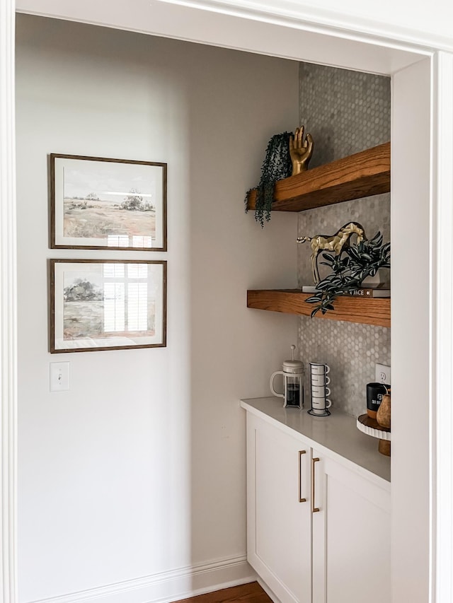bar featuring baseboards and backsplash