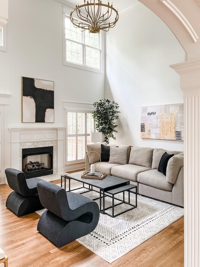 living room featuring a high ceiling, a notable chandelier, wood finished floors, and a fireplace