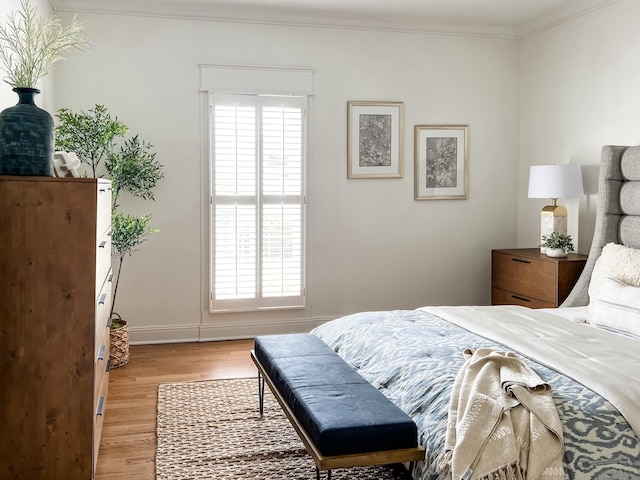 bedroom with crown molding, baseboards, multiple windows, and light wood-style flooring