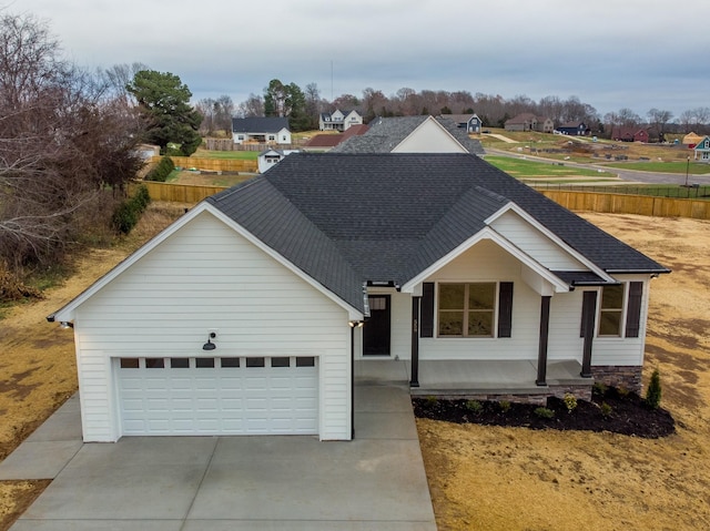 ranch-style home with a garage, driveway, fence, and roof with shingles