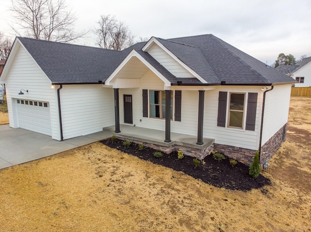 single story home with an attached garage, covered porch, a shingled roof, and driveway