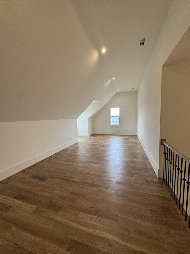 bonus room with baseboards, vaulted ceiling, and dark wood-style flooring