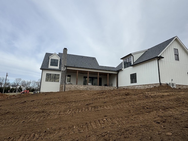 rear view of property with a shingled roof and a chimney