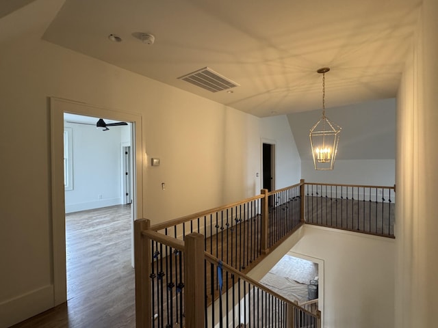 corridor with visible vents, an inviting chandelier, an upstairs landing, wood finished floors, and baseboards