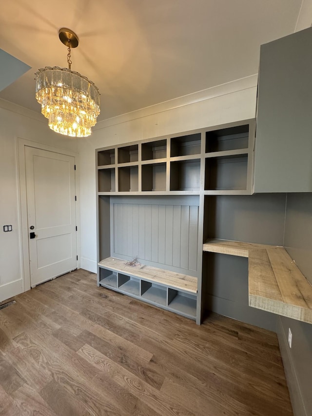 mudroom with a chandelier, wood finished floors, and crown molding