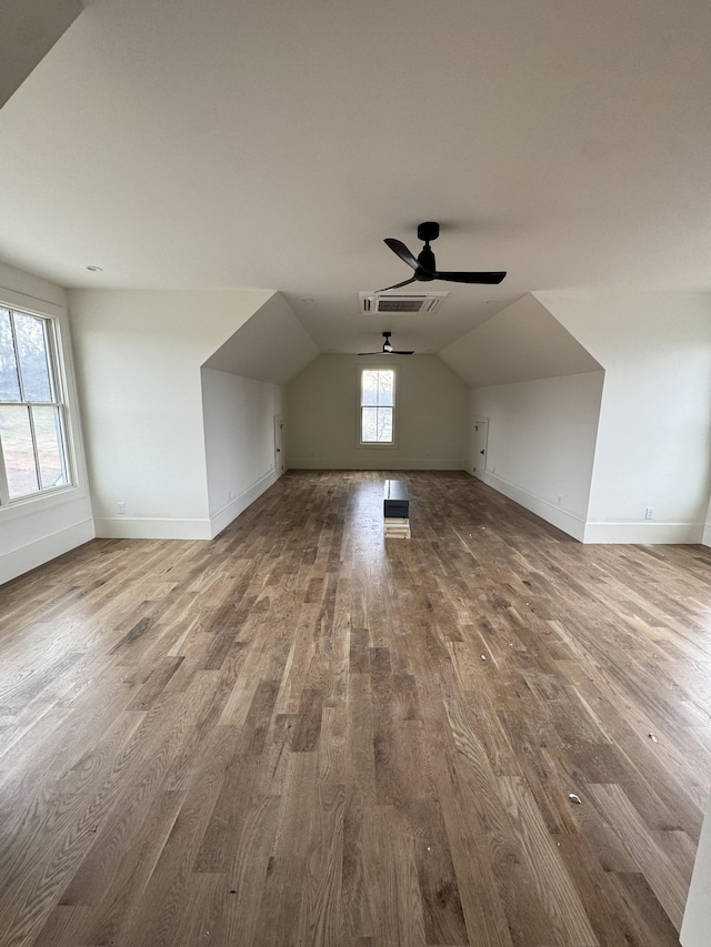 additional living space featuring lofted ceiling, wood finished floors, visible vents, and baseboards