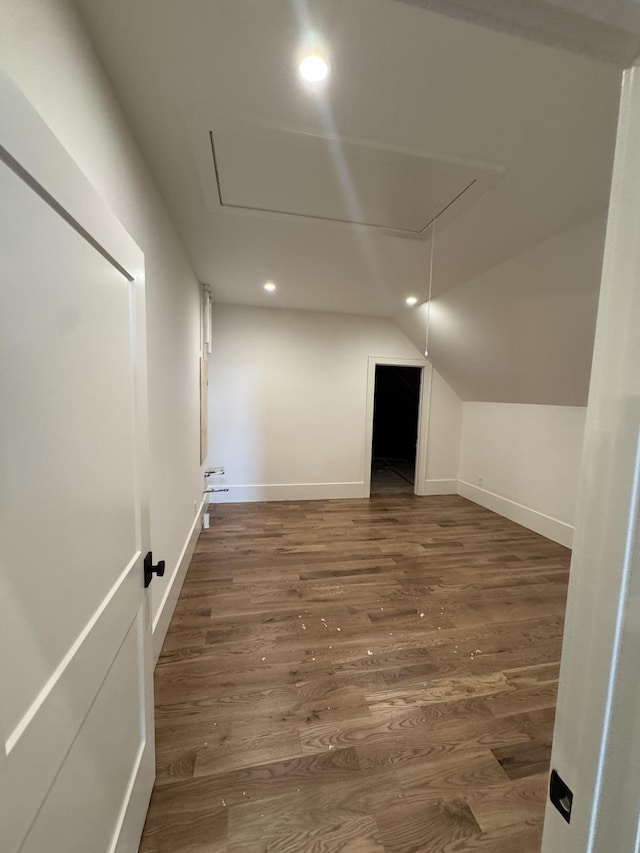 additional living space featuring attic access, lofted ceiling, baseboards, and wood finished floors