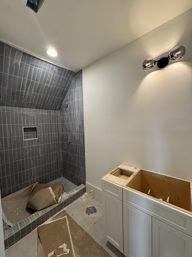 full bathroom with vaulted ceiling and a tile shower