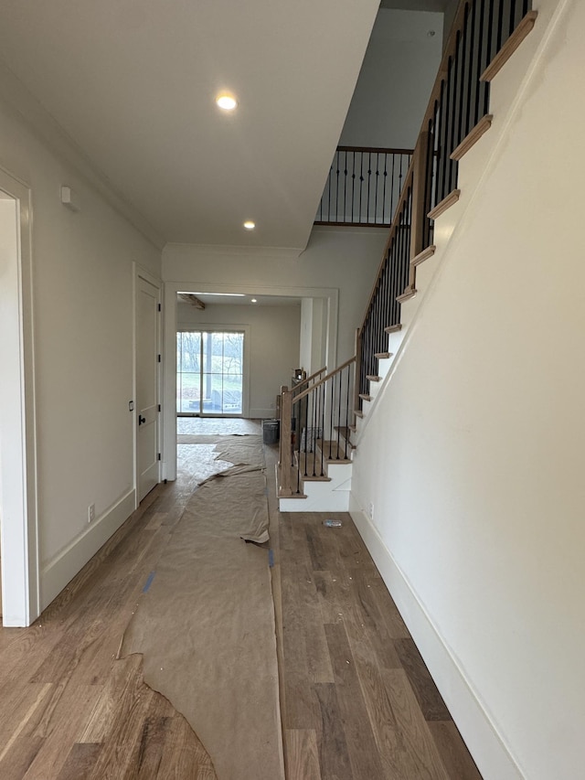 hall with stairs, recessed lighting, baseboards, and wood finished floors