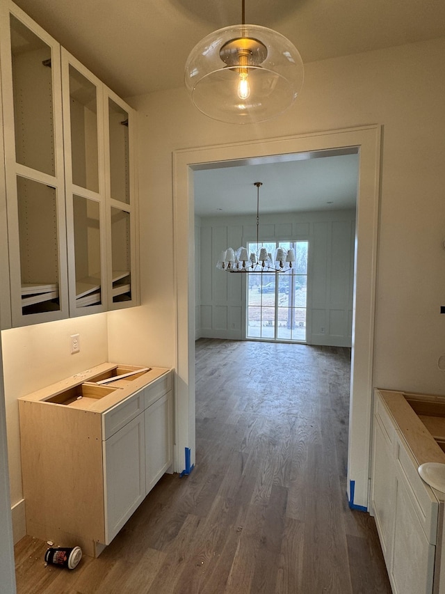 unfurnished dining area featuring a notable chandelier and dark wood-style flooring