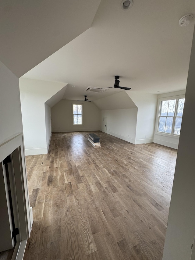 additional living space with lofted ceiling, light wood-style flooring, baseboards, and ceiling fan