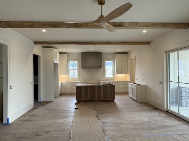 kitchen with light wood finished floors, baseboards, beam ceiling, and a center island