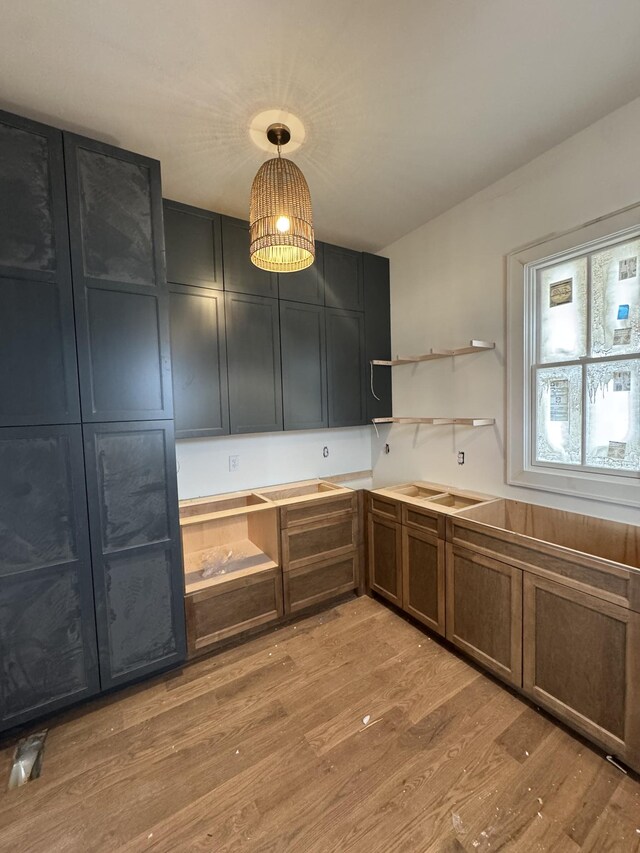 kitchen featuring open shelves, a sink, light wood-style flooring, and pendant lighting