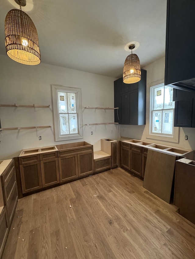 kitchen featuring light wood-style floors, light countertops, decorative light fixtures, and open shelves