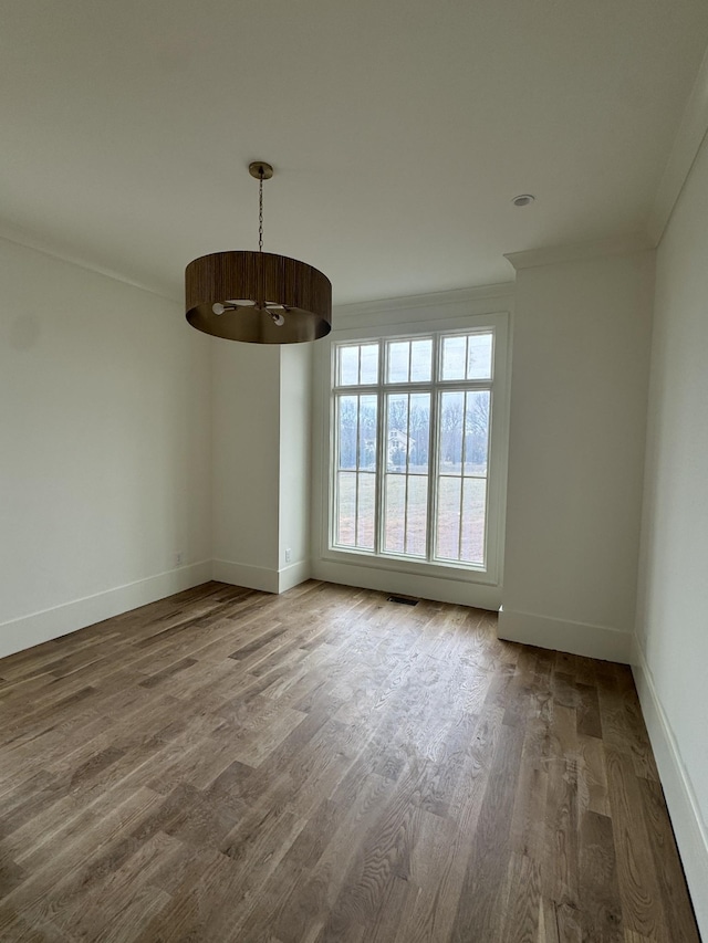 spare room featuring ornamental molding, wood finished floors, and baseboards