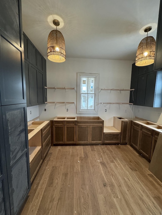 kitchen featuring pendant lighting, a notable chandelier, light wood-style flooring, and open shelves