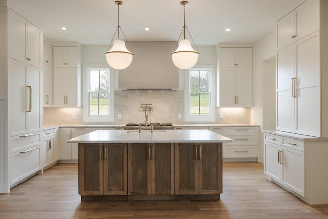 kitchen featuring a center island with sink, light countertops, light wood-style floors, and a wealth of natural light
