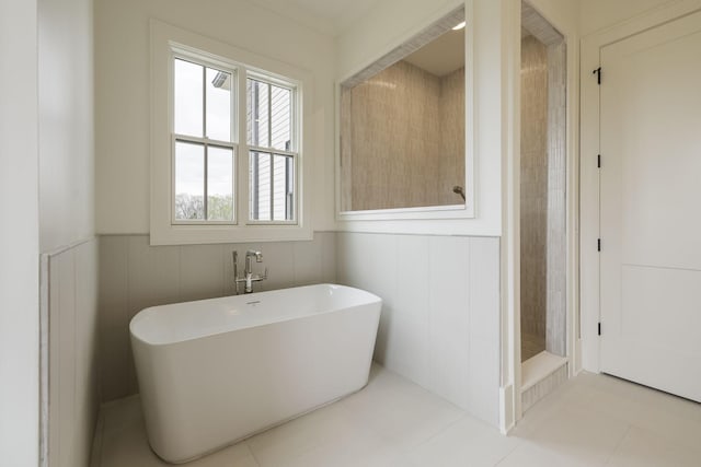 bathroom with tile patterned flooring, a freestanding tub, a stall shower, and wainscoting