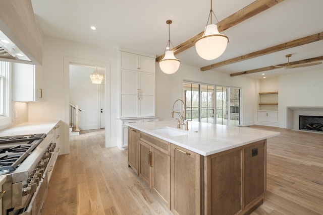 kitchen with custom exhaust hood, beamed ceiling, a sink, high end stainless steel range, and light wood-type flooring