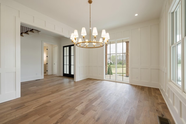unfurnished room with a decorative wall, visible vents, recessed lighting, light wood-type flooring, and an inviting chandelier