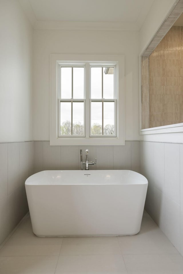 full bath with a wainscoted wall, tile patterned flooring, and a freestanding bath