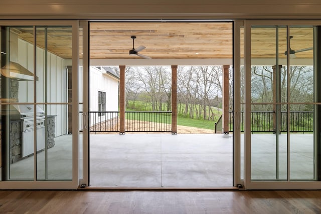 doorway with wood finished floors and ceiling fan