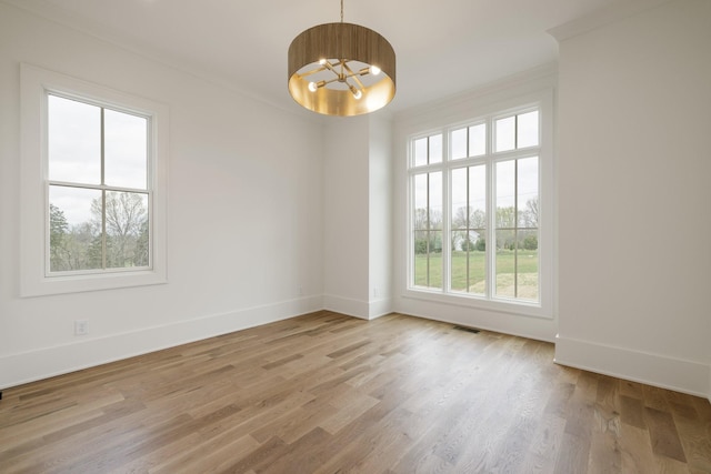 unfurnished room featuring crown molding, baseboards, a chandelier, and wood finished floors