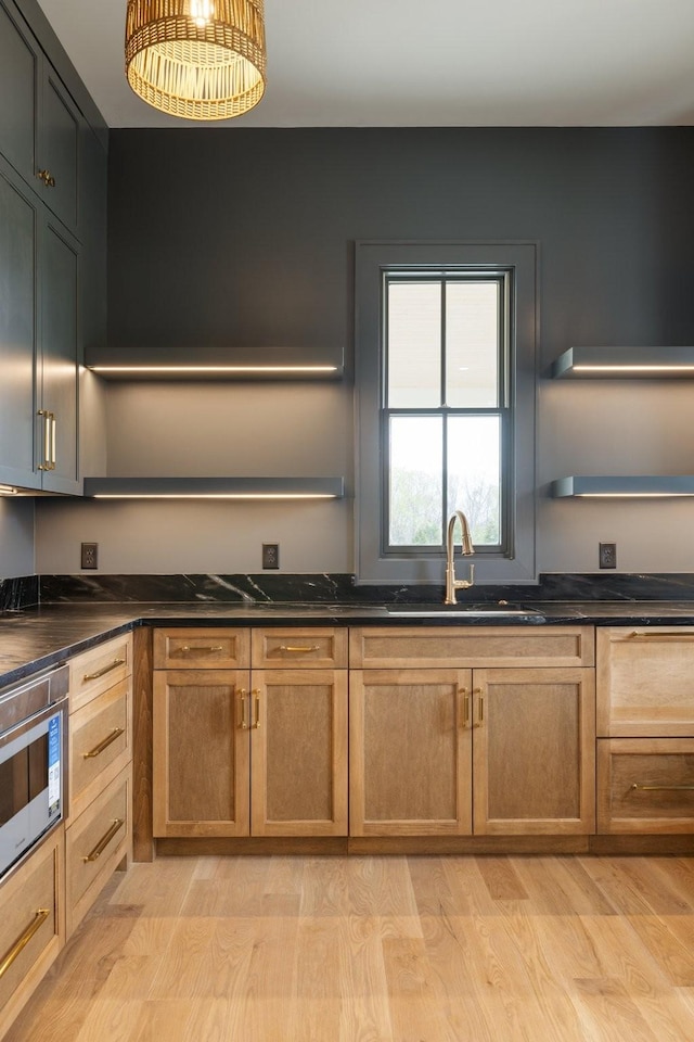 kitchen featuring light wood-style floors, a sink, and open shelves