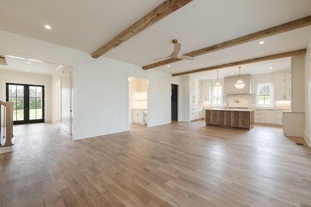 unfurnished living room with recessed lighting, light wood-type flooring, baseboards, beam ceiling, and a ceiling fan