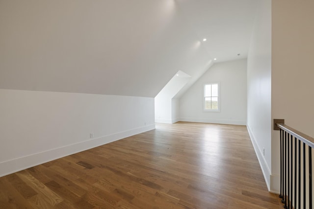 additional living space featuring baseboards, lofted ceiling, wood finished floors, and recessed lighting