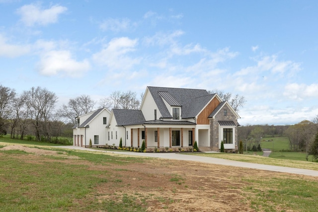 modern farmhouse featuring a front yard, roof with shingles, concrete driveway, board and batten siding, and a garage