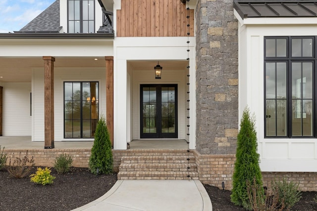 property entrance with stone siding, a porch, and a shingled roof