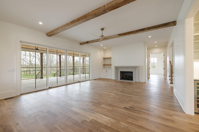 unfurnished living room featuring light wood-style flooring, baseboards, beam ceiling, visible vents, and a ceiling fan