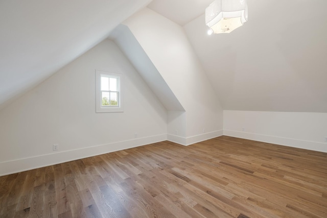 additional living space featuring baseboards, lofted ceiling, and light wood-style flooring