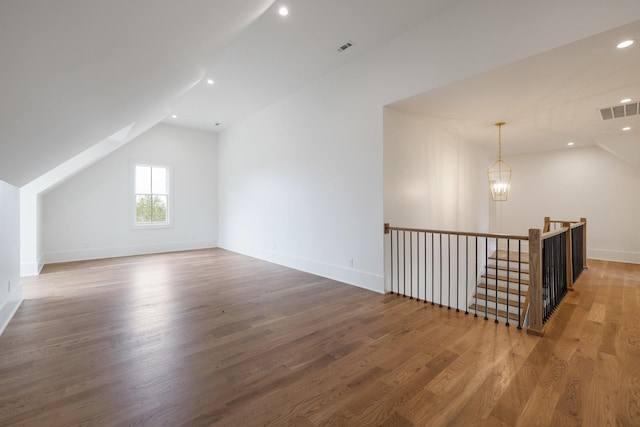 bonus room with baseboards, visible vents, vaulted ceiling, and wood finished floors