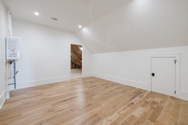 additional living space featuring vaulted ceiling, baseboards, visible vents, light wood-style floors, and recessed lighting