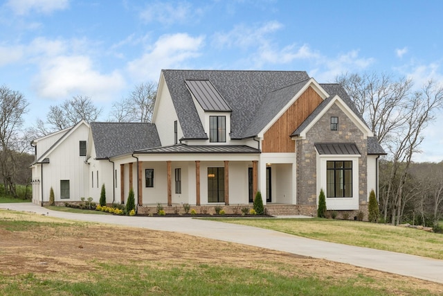 modern inspired farmhouse featuring a standing seam roof, concrete driveway, roof with shingles, a front lawn, and metal roof
