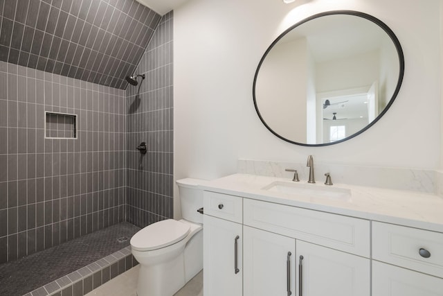 bathroom featuring toilet, tiled shower, and vanity