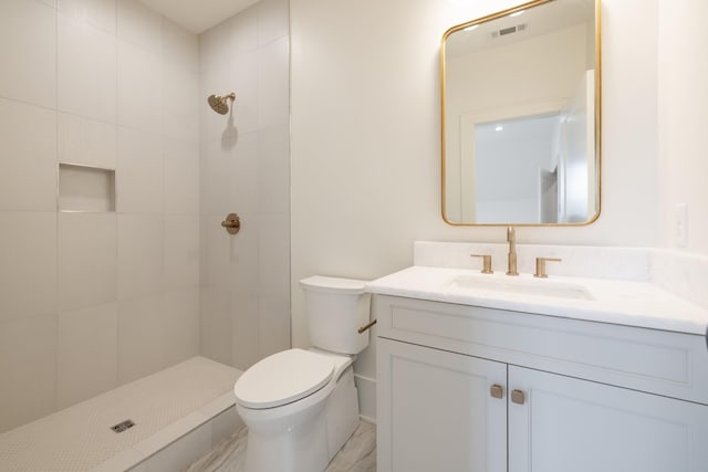 bathroom with visible vents, toilet, tiled shower, and vanity