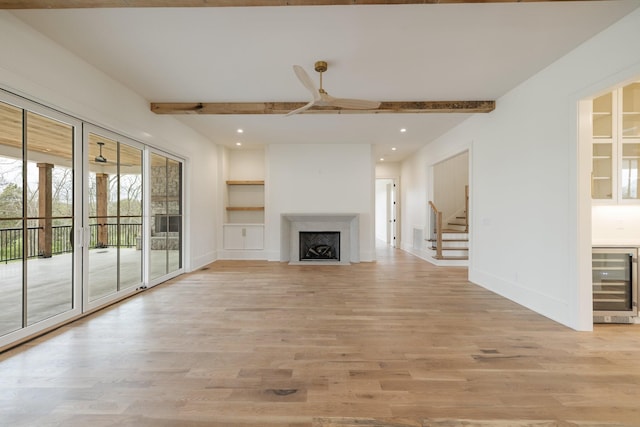 unfurnished living room with beam ceiling, wine cooler, and light wood finished floors