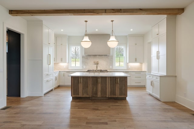 kitchen with decorative backsplash, custom range hood, beamed ceiling, and plenty of natural light