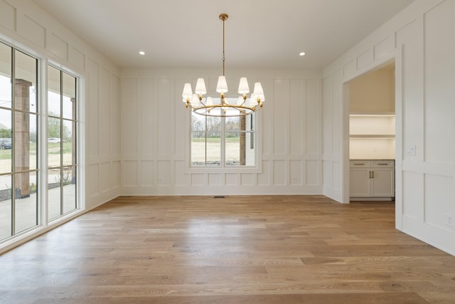 unfurnished dining area with recessed lighting, an inviting chandelier, light wood finished floors, visible vents, and a decorative wall