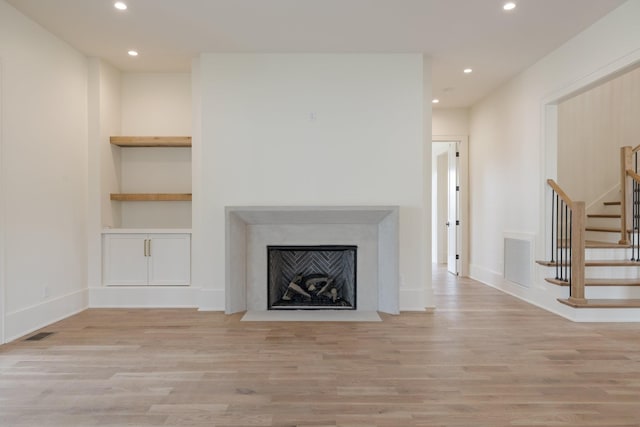unfurnished living room featuring light wood finished floors, visible vents, recessed lighting, and stairway