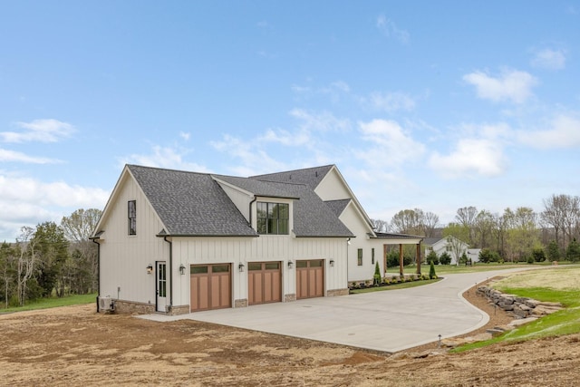 view of side of home with concrete driveway, a garage, and roof with shingles