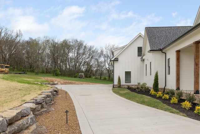 view of home's exterior with driveway, a shingled roof, and a yard