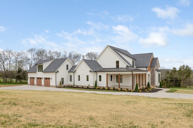 modern farmhouse style home with a standing seam roof, metal roof, driveway, a front lawn, and covered porch