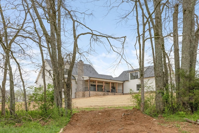 back of house featuring covered porch and roof with shingles