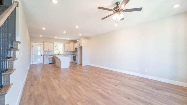 unfurnished living room with light wood finished floors, baseboards, and recessed lighting