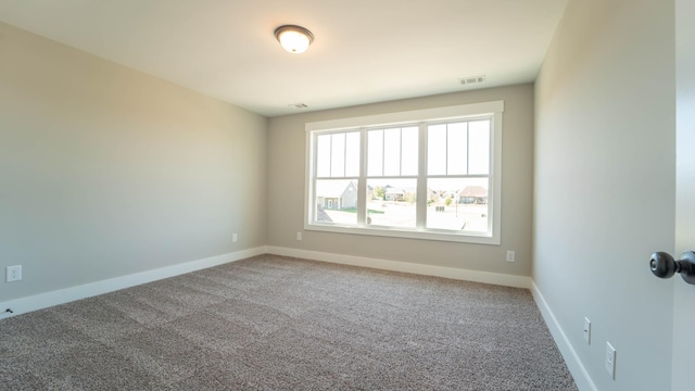 carpeted spare room featuring visible vents and baseboards