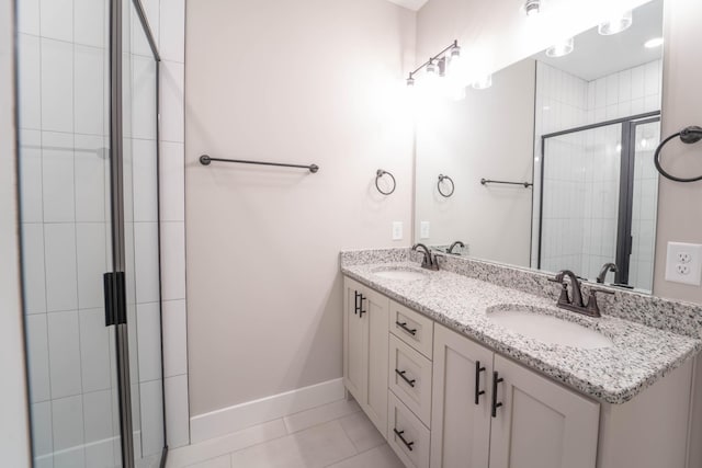 bathroom featuring baseboards, tile patterned floors, a sink, and a shower stall